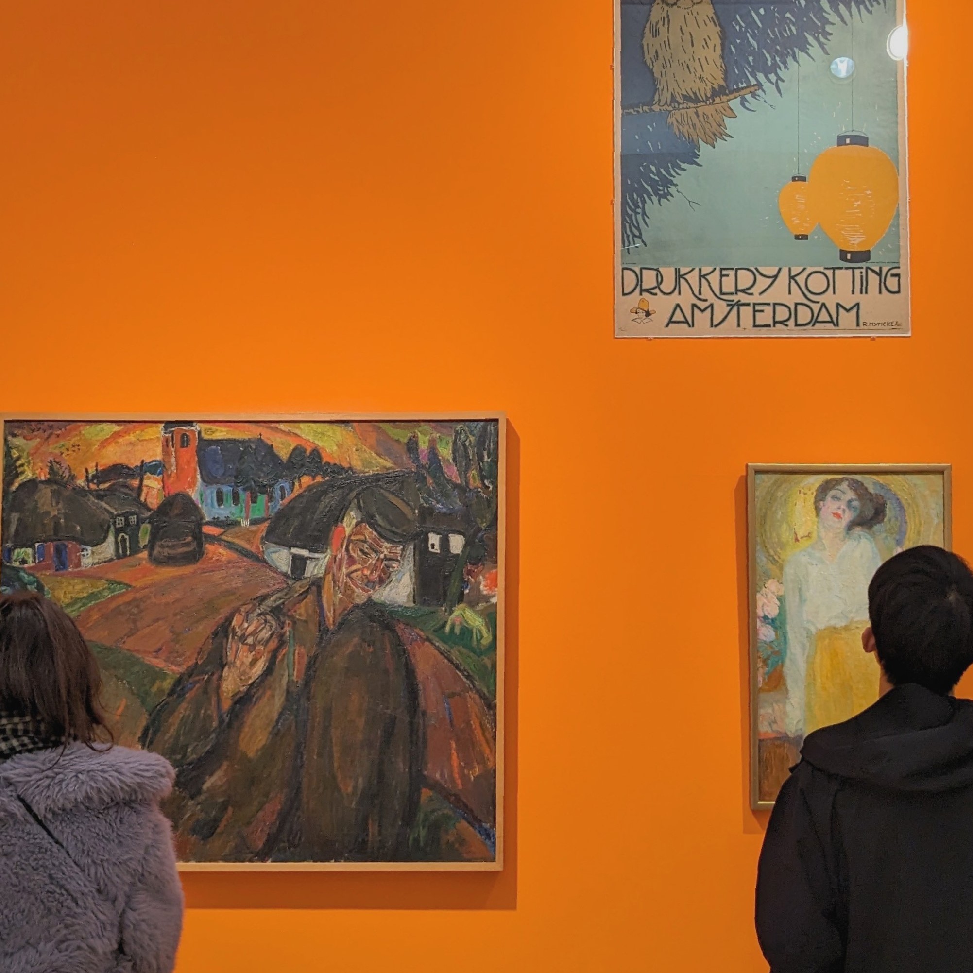 paintings hanging on a orange wall in a museum